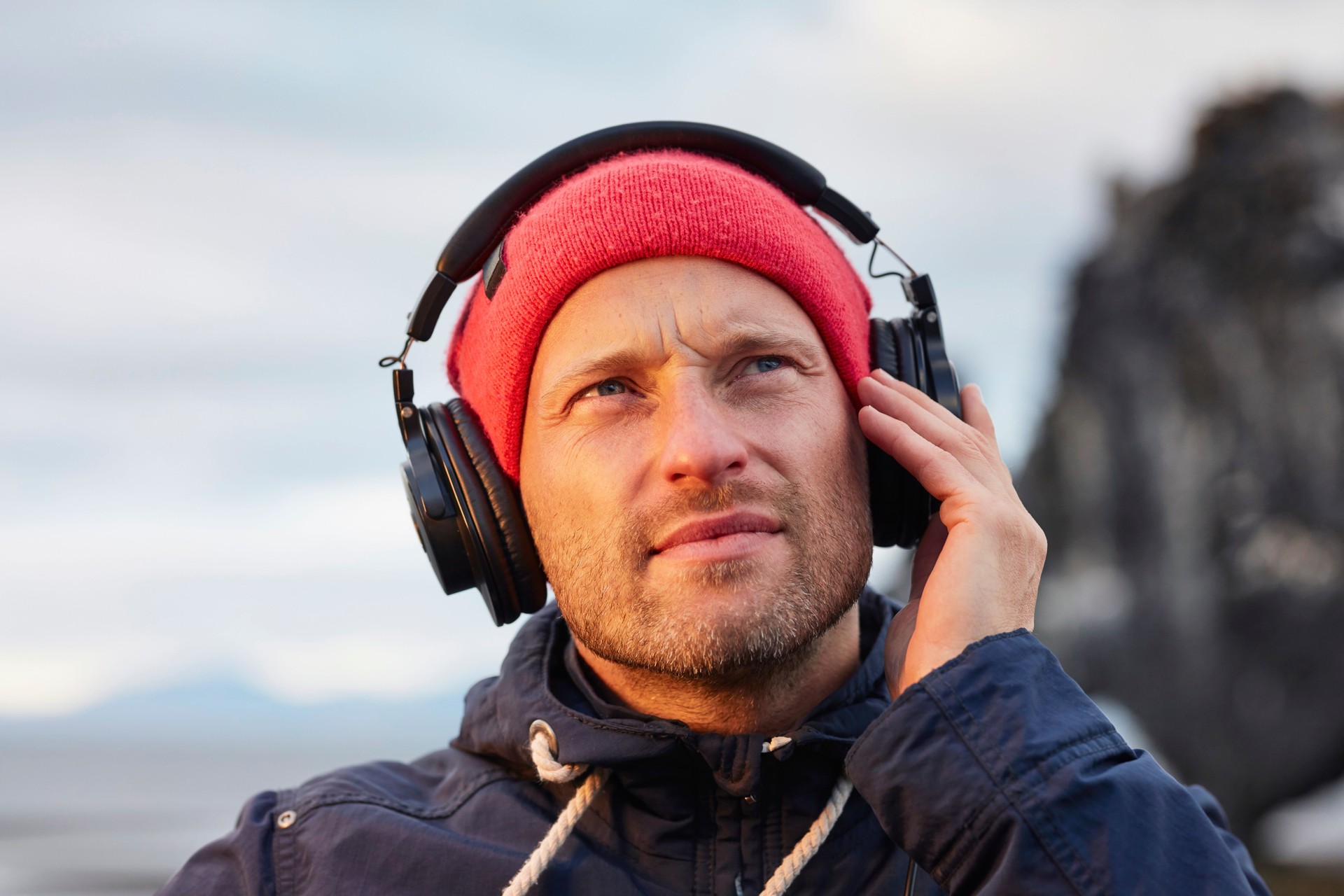 Young man enjoying music on a beautiful black beach